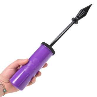 Pompe manuelle violette pour gonfler des ballons, avec embout noir, tenue par une main sur fond blanc.