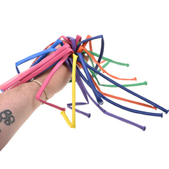 Main tenant un faisceau de ballons longs 260 Sempertex multicolores (rose, bleu, jaune, violet, vert et orange), prêt à être gonflé — kit Ballons Sempertex 260 + Pompe.