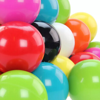 Gros plan sur un empilement de balles de contact multicolores brillantes (rouge, bleu, vert, jaune, orange, blanc, noir et rose) du kit de jonglerie débutant.
