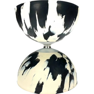 Diabolo Arlequin en couleur noir et blanc, avec un design de coups de pinceau. Il a une forme en sablier, avec une partie supérieure et inférieure arrondie, et un axe central en métal.