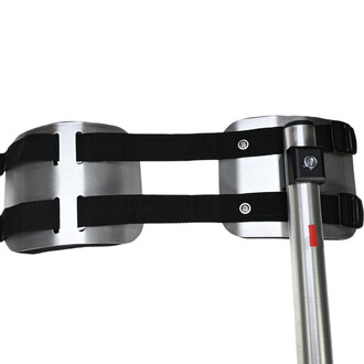 Kit de molletière avec sangles, composé de deux éléments métalliques argentés attachés par des sangles noires. Visible un dispositif de fixation sur un tube, adapté pour la pratique du jonglage.