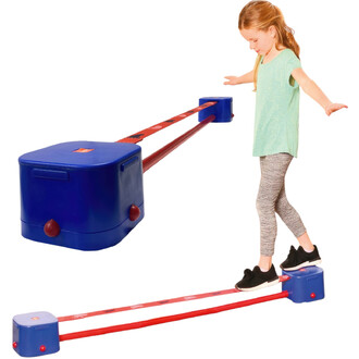 Une jeune fille en t-shirt vert clair marche sur une slackline rouge, avec un équilibre précaire. Elle est positionnée entre deux supports bleus, qui maintiennent la slackline. Ses jambes sont en leggings rayés et elle porte des chaussures noires. L'image