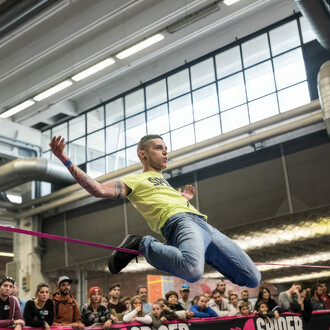 Acrobatie sur slackline rose dans un gymnase avec du public
