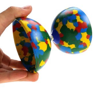 Diabolo Jester Lumineux Fluxo, présenté dans une main, avec une surface colorée en motifs avec des éclats de rouge, jaune, bleu et vert. Les deux parties du diabolo sont reliées par un axe central, ce qui est typique des équipements de jonglerie.