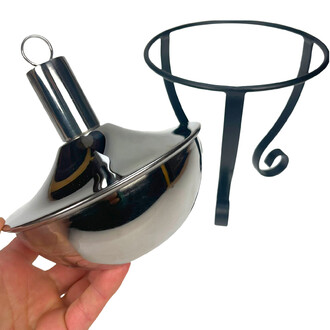 Lampe à huile torchière en métal poli avec réservoir bombé et cylindre à anneau, tenue dans une main sur fond blanc.