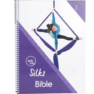 Couverture violette et blanche d’un carnet spiralé « Silks Bible » montrant une artiste en tenue bleue effectuant une figure d’acrobatie suspendue à des tissus violets.