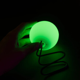 Main tenant une sphère LED verte lumineuse sur fond sombre, avec un cordon spiralé en dessous.