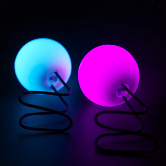 Lumi Pro LED Palms, deux boules lumineuses, une de couleur bleu clair et l'autre rose, posées sur un fond sombre. Chaque boule est maintenue par un support en spirale noir.