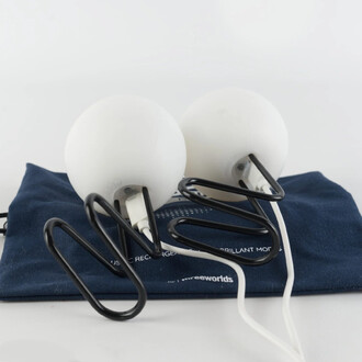 Deux lumières LED rondes blanches avec des supports en métal noir, posées sur un sac bleu. Les lumières sont reliées par des câbles, et le sac affiche une inscription.