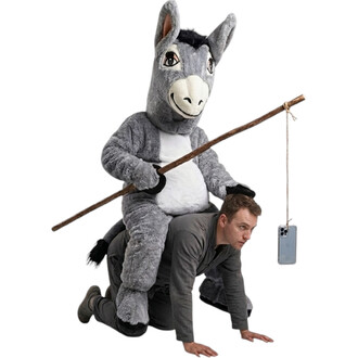 Mascotte âne gris en peluche sur le dos d’un homme à quatre pattes, tenant un long bâton avec un téléphone accroché par une corde.