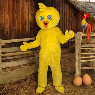 Mascotte de poussin en costume jaune vif, avec des yeux ronds et un grand sourire, se tenant debout dans une ferme. En arrière-plan, on peut voir des barrières en bois et des œufs au sol. Une décoration de coq en jouet est également visible à côté de la m