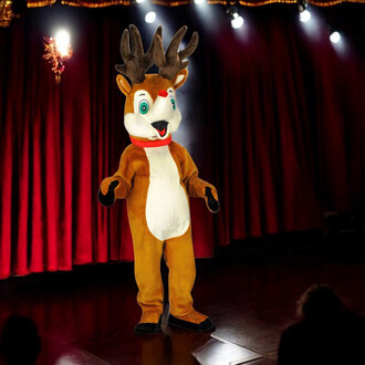 Mascotte de renne de Noël en costume coloré, avec des grandes oreilles et des bois. Le personnage se tient sur scène, devant un rideau rouge, avec une expression amicale.