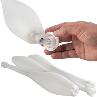 Plan rapproché d'une massue Lumi Pro ThreeWorlds : une main dévisse le bouchon transparent à l'extrémité pour accéder au connecteur, deux massues blanches reposant en arrière-plan.