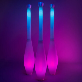 Trois massues lumineuses Massue Lumi Pro de ThreeWorlds, éclairées en bleu et magenta sur fond sombre.