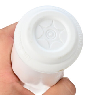 Vue du dessous d'une massue de jonglerie blanche, tenue dans une main. Le dessous présente un motif en étoile avec des inscriptions sur le bord.