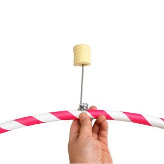 Mèche de feu Threeworlds, cylindre de corde beige fixée à une tige métallique au-dessus d’un hula hoop rose et blanc tenu par une main.