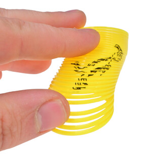 Mini Springy Dinosaure de couleur jaune en forme de spirale, tenant entre les doigts.