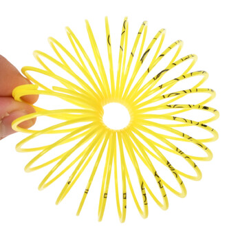 Mini Springy Licorne, un jouet en spirale jaune vif, tenu par une main, formant une forme circulaire avec des spirales à rayons.