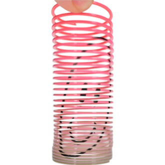Mini Springy Smiley, un ressort en plastique coloré de couleur rose, portant une façade avec un visage souriant dessiné en noir, tenu par une main.