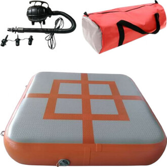 Module gonflable Sarneige, comprenant un tapis de réception de forme carrée avec une surface grise et des motifs orange, un souffleur noir pour le gonflage, et un sac de transport rouge et blanc.