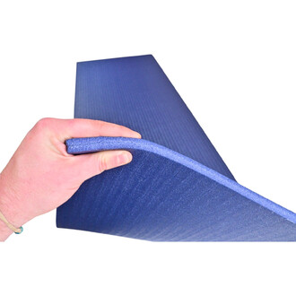 Main tenant une natte de jonglerie Grand Confort de 15 mm d'épaisseur, de couleur bleue, avec une texture légèrement striée. L'image met en avant la flexibilité et la qualité du matériau.