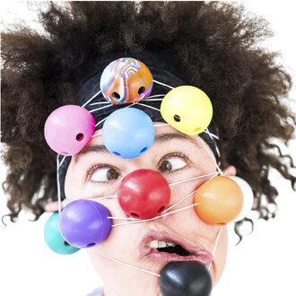 Un visage de clown amusant avec des boules en silicone colorées fixées sur un chapeau, les yeux écarquillés et une expression faciale drôle, entouré de fils blancs.