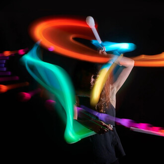 Personne en train de jongler avec des nunchakus LED, créant des traînées de lumière colorées dans un environnement sombre. Des mouvements fluides et dynamiques se dégagent de l'image, mettant en valeur l'effet lumineux des nunchakus.