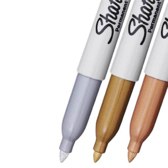 Trois marqueurs Sharpie métalliques avec capuchons blancs, en nuances argent, doré et cuivre, alignés en diagonale.