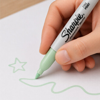 Marqueur Sharpie Pastel vert menthe à pointe fine, tenu par une main et dessinant une ligne ondulée sur du papier blanc.