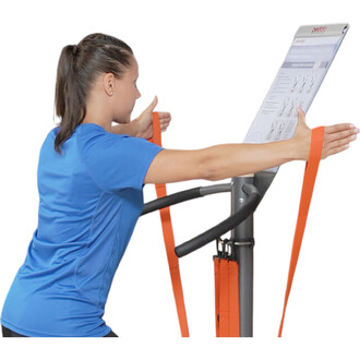 Femme en t-shirt bleu utilisant un appareil de sport avec des bandes élastiques orange, elle est en position d'exercice avec les bras étendus, face à un tableau d'instructions visible au-dessus.