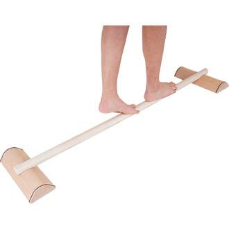 Barre d'équilibre en bois avec deux supports aux extrémités, sur laquelle une personne se tient en équilibre sur les pieds.