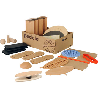 Kit de jeu Pedalo comprenant divers éléments en bois et en matière composite, placé dans un carton marqué Made in Germany. On y trouve des cylindres en bois, des planches à bascule, des formes variées, ainsi qu'un ensemble de pièces de différentes texture