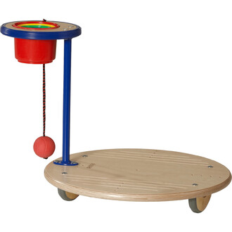 Plateforme de jonglerie en bois avec un support bleu et un seau rouge. Un filet suspendu maintient une balle rouge. La plateforme est ronde et montée sur roulettes pour un usage dynamique.