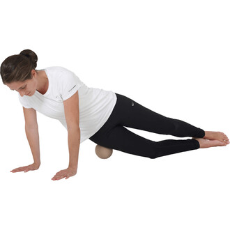 Femme en position de yoga sur le côté, utilisant une balle de massage. Elle porte un t-shirt blanc et un legging noir, avec les bras en appui sur le sol. La balle est placée sous sa cuisse. Fond blanc.