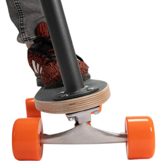 Détail d'un pied posé sur un plateau de skate avec des roues orange vif. La tige du skate est noire et le plateau en bois clair. Le pied est vêtu d'une chaussure à motifs rouges et noirs.