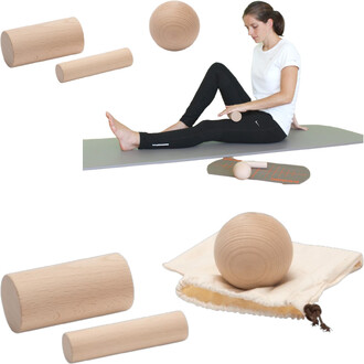 Image du kit de massage Pedalo® comprenant plusieurs rouleaux et balles en bois, avec une personne assise sur un tapis, utilisant un des accessoires pour un massage. Le set est présenté avec des éléments supplémentaires, y compris un sac en tissu pour le 