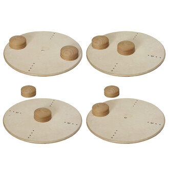 Quattro dischi circolari in legno chiaro, ciascuno con sopra una pila di due piccoli pezzi di legno marrone chiaro. I dischi presentano punti perforati in vari punti, che suggeriscono possibili opzioni di fissaggio o aggancio.
