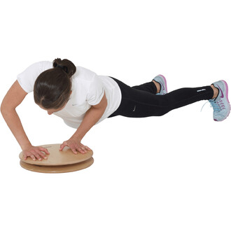 Femme en position d'exercice, effectuant des mouvements de pompes sur un Pedalo® Twister 380, un plateau en bois circulaire. Elle porte un t-shirt blanc, un legging noir et des chaussures de sport multicolores.