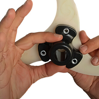 Deux mains tiennent un élément de jonglerie, un Plug Hub de Flowbonacci, avec une partie noire et des attaches blanches. Le focus est sur la connexion entre les pièces, illustrant la conception modulaire.