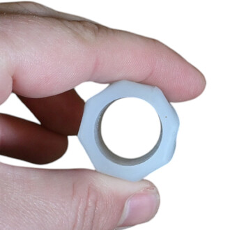 Premier plan d'un petit anneau en silicone bleu clair, forme carrée avec coins arrondis et trou central, tenu entre les doigts.