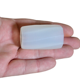 Petit poids en silicone gris clair, forme rectangulaire à coins arrondis, tenu entre les doigts.