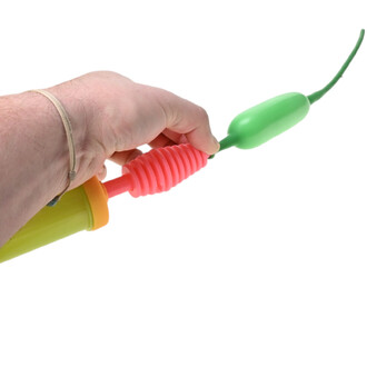 Main tenant une pompe double action Pocket Balloon miniature, corps vert, embout vert, gaine rose côtelée et bouchon orange, vue de profil.