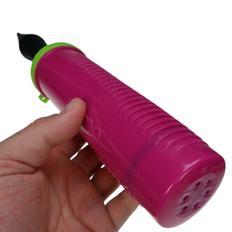 Pompe à main double action de couleur rose vif, avec une poignée texturée pour une prise en main confortable. Le sommet est équipé d'un embout noir, et un anneau vert entoure la base. La pompe est tenue à la main, mettant en avant sa taille compacte.