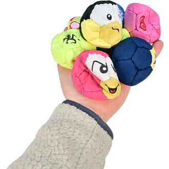 Main tenant plusieurs balles de jonglerie TSHAKA multicolores, comprenant des visages amusants et des motifs variés, avec un fond blanc.