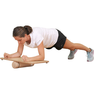 Femme effectuant un exercice de planche sur une plateforme en bois, utilisant un rouleau comme support, vêtue d'un t-shirt blanc et de shorts noirs, avec des chaussures de sport.