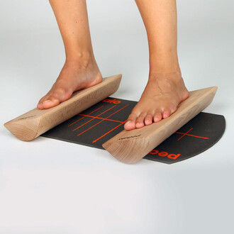 Pieds nus posés sur deux planches en bois sur un tapis gris dessus, avec des lignes orange pour guider les mouvements.