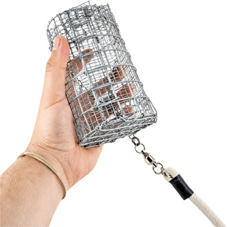 Main tenant une cage cylindrique en fil métallique argenté du Rope Dart Cage Gora, avec chaîne et corde beige visibles.