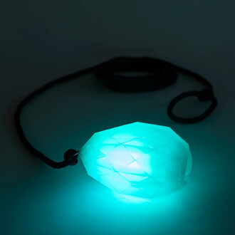 Perle lumineuse en forme de diamant de couleur turquoise, attachée à une corde noire, avec un éclairage LED émettant une lueur brillante dans un environnement sombre.