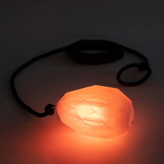 Rope Dart LED Prism de Threeworlds, affichant une tête en forme de diamant émettant une lumière orange, attachée à une corde noire, sur un fond sombre.