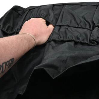 Main saisissant un sac à ballons noir en tissu, montrant l'ouverture élastiquée et les plis du matériau.